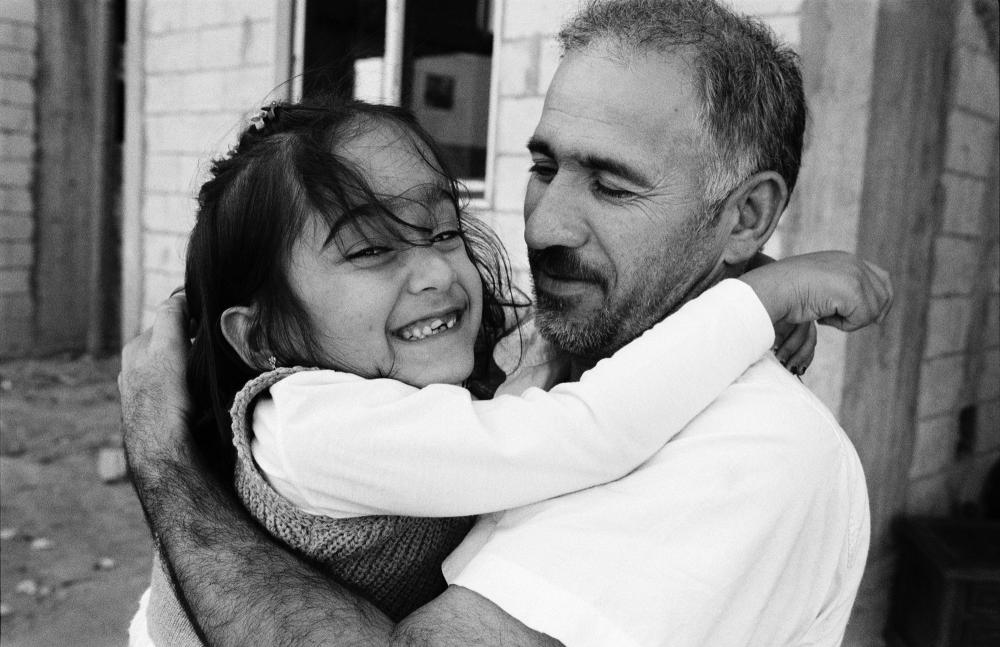 On this picture by Giles Duley taken in 2016. Aya, a young Syrian refugee, hugs her father as they prepare to be resettled from Lebanon to France.  